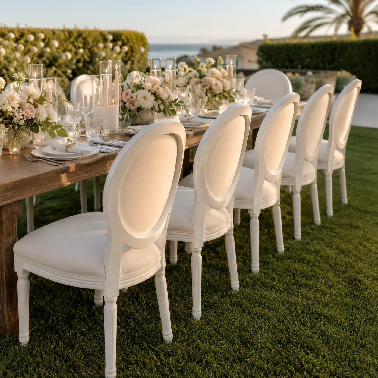 Elegant dining chair rentals in Orange County, California, arranged beside a decorated outdoor banquet table with flowers, candles, and glassware.